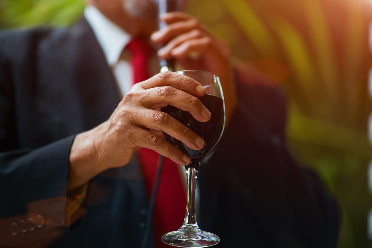 High functioning alcoholism. An image of a man in a suit holding a glass of red wine.