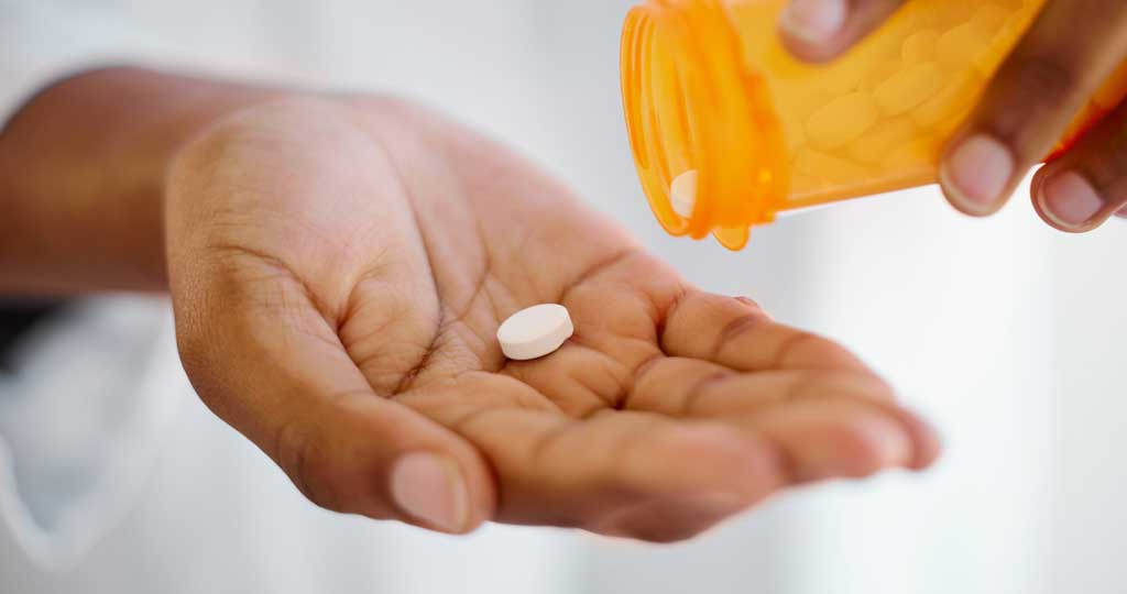 A lady putting a prescription pill in her hand