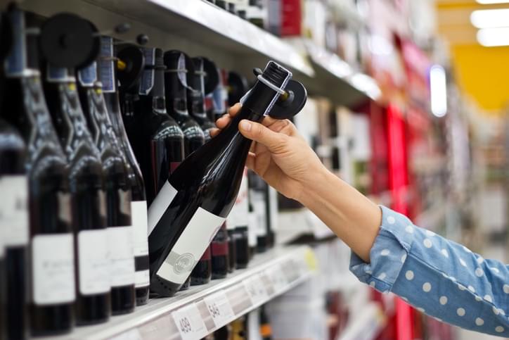 Woman is buying a bottle of wine at the supermarket background