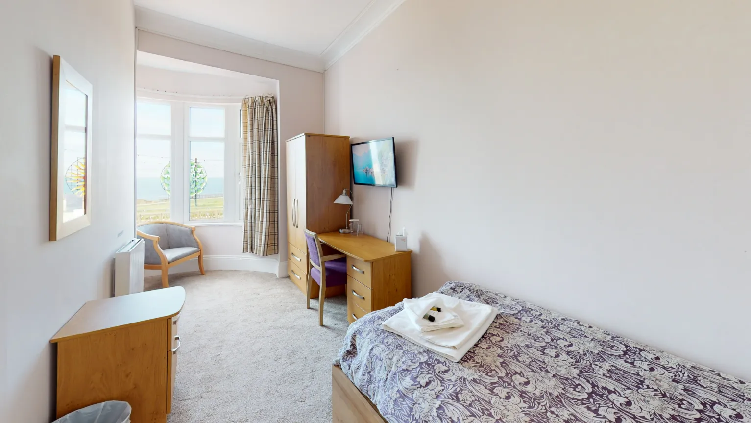 Bedroom in the rehabilitation residential treatment centre, Ocean Recovery, with a view of the garden and a television.