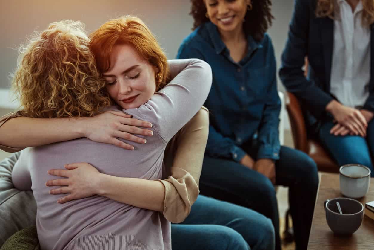 Two women at a support group hugging