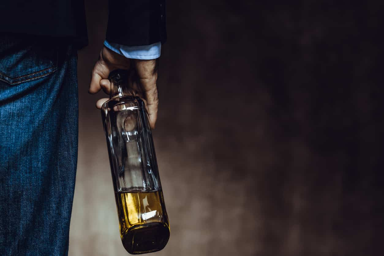 male handing holding a bottle with yellow liquid