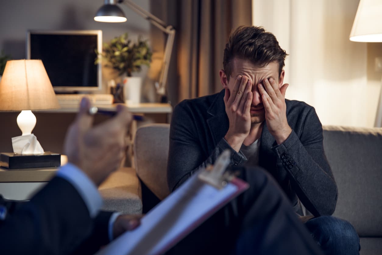 Man burying face in hands during therapy session