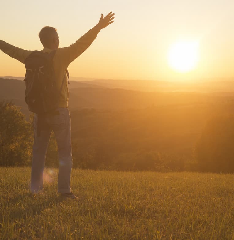 man on field in sunset joyful