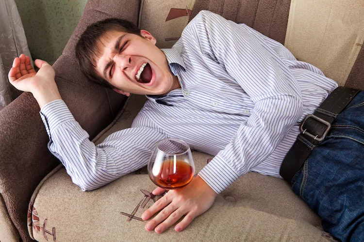 Man with a glass of alcohol yawning