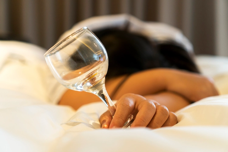 woman passed out holding a glass of wine