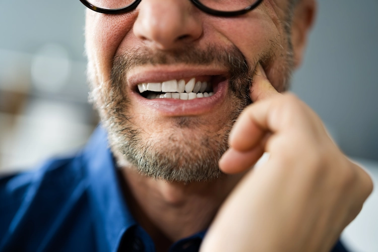 A man holding his tooth with tooth decay