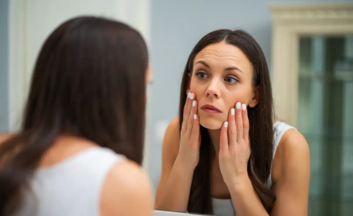 How Quitting Alcohol Changes Your Appearance - An image of a woman looking at her skin in the mirror