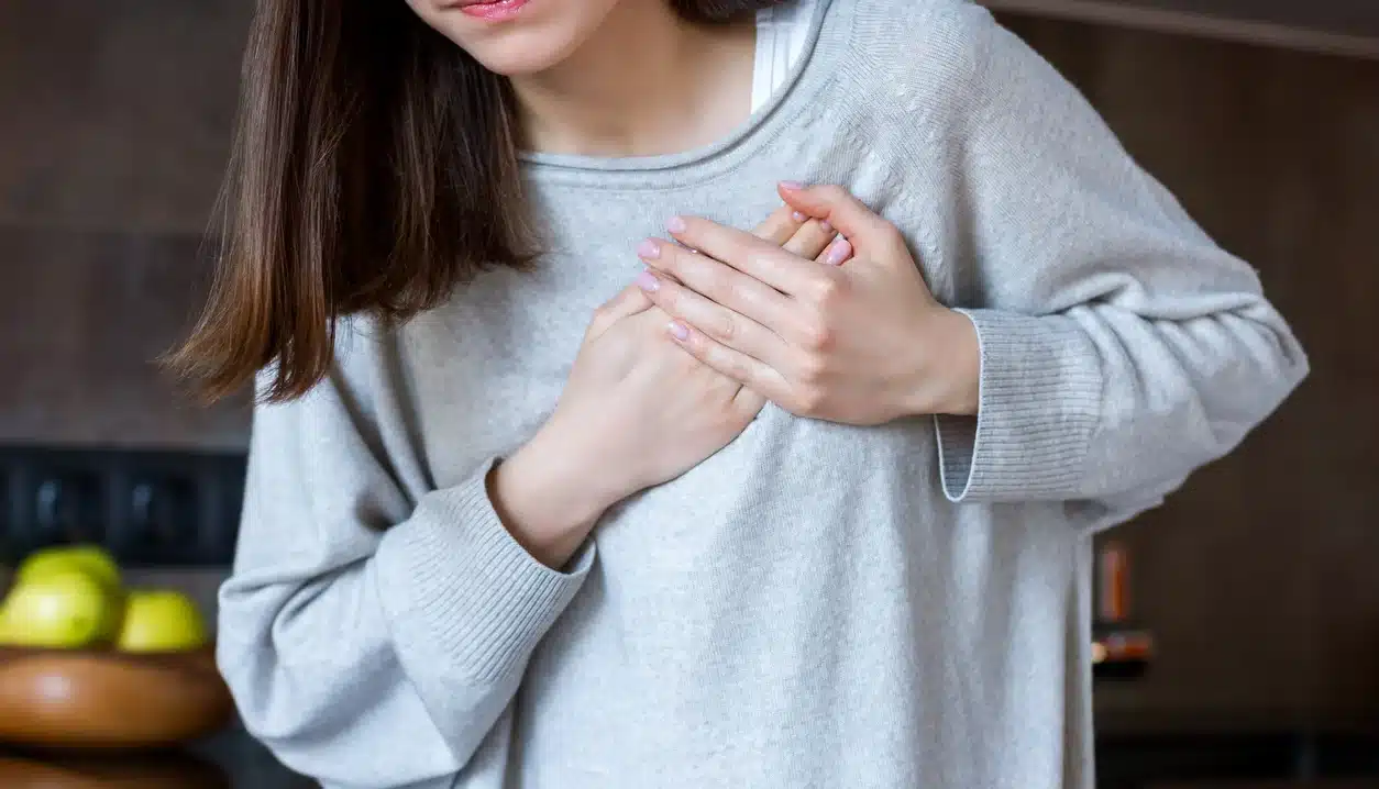 A woman holding her chest, experiencing chest pain.
