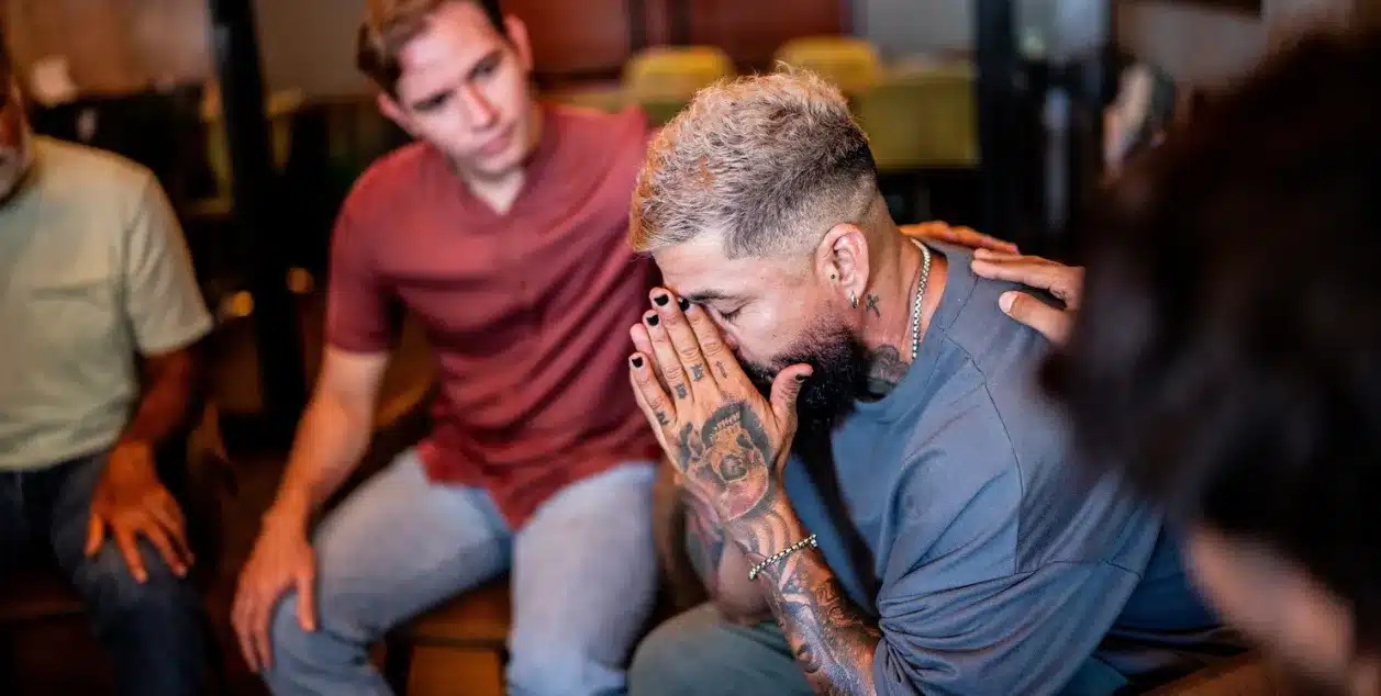 Is Addiction Considered a Chronic Illness? Image of a man being comforted in a group therapy