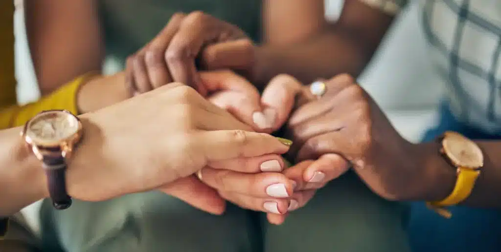 What Role Could AI Play in Treating Addictions? Support group holding hands.