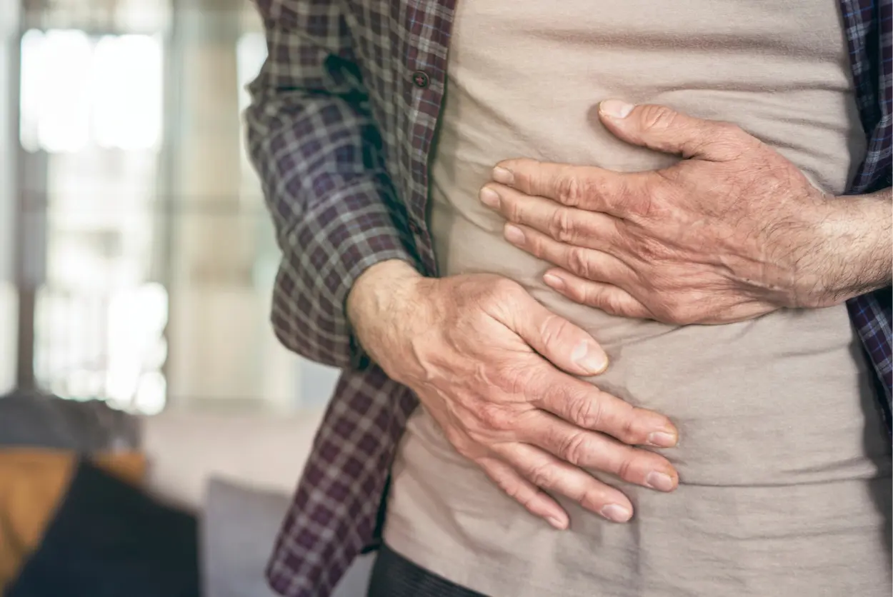 Torso of a man clutching his stomach because of abdominal pain